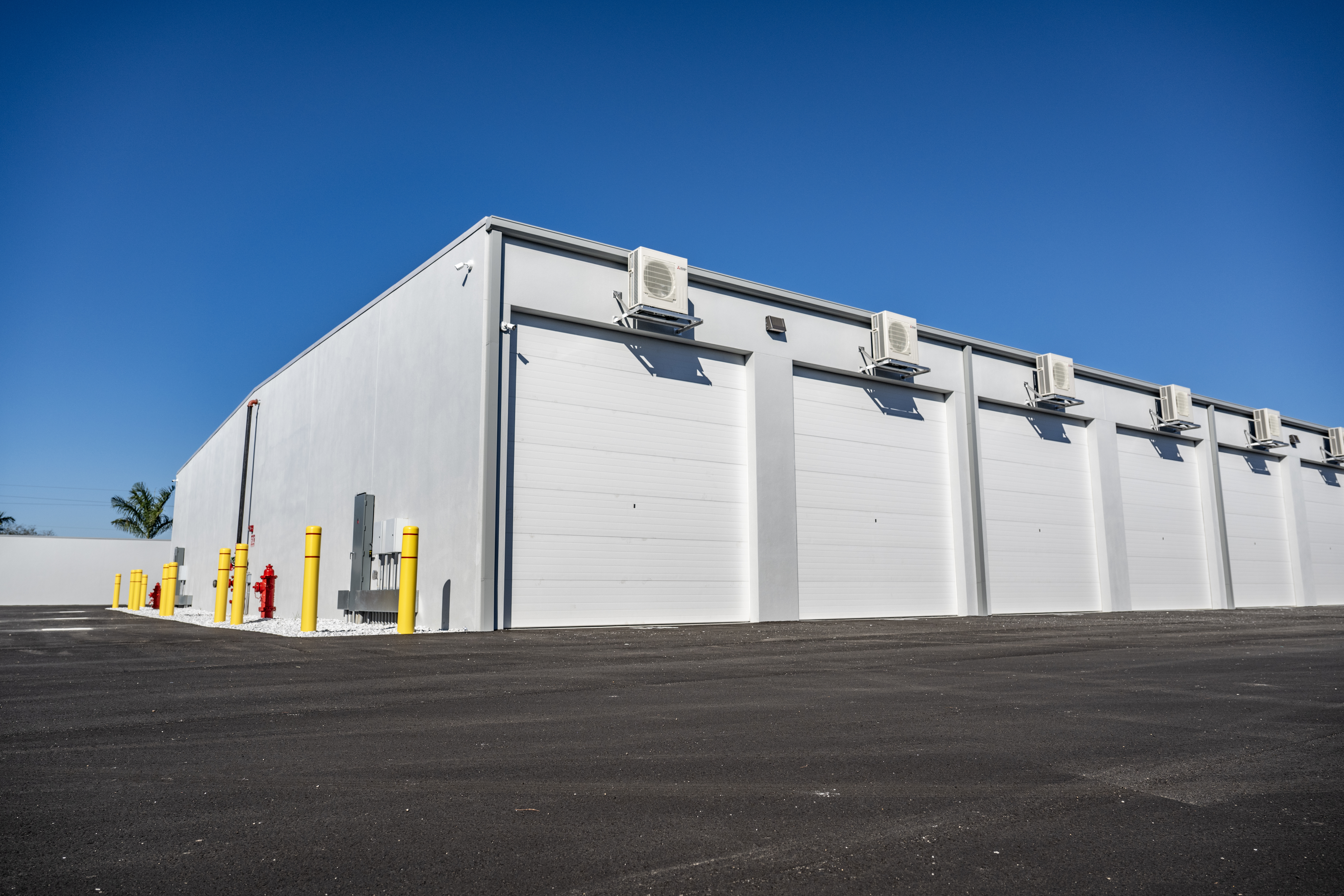 Exterior view of MetroMaxx climate-controlled RV and boat storage building with large roll-up doors, individual HVAC units, and wide paved access lanes in Fort Myers, Florida
